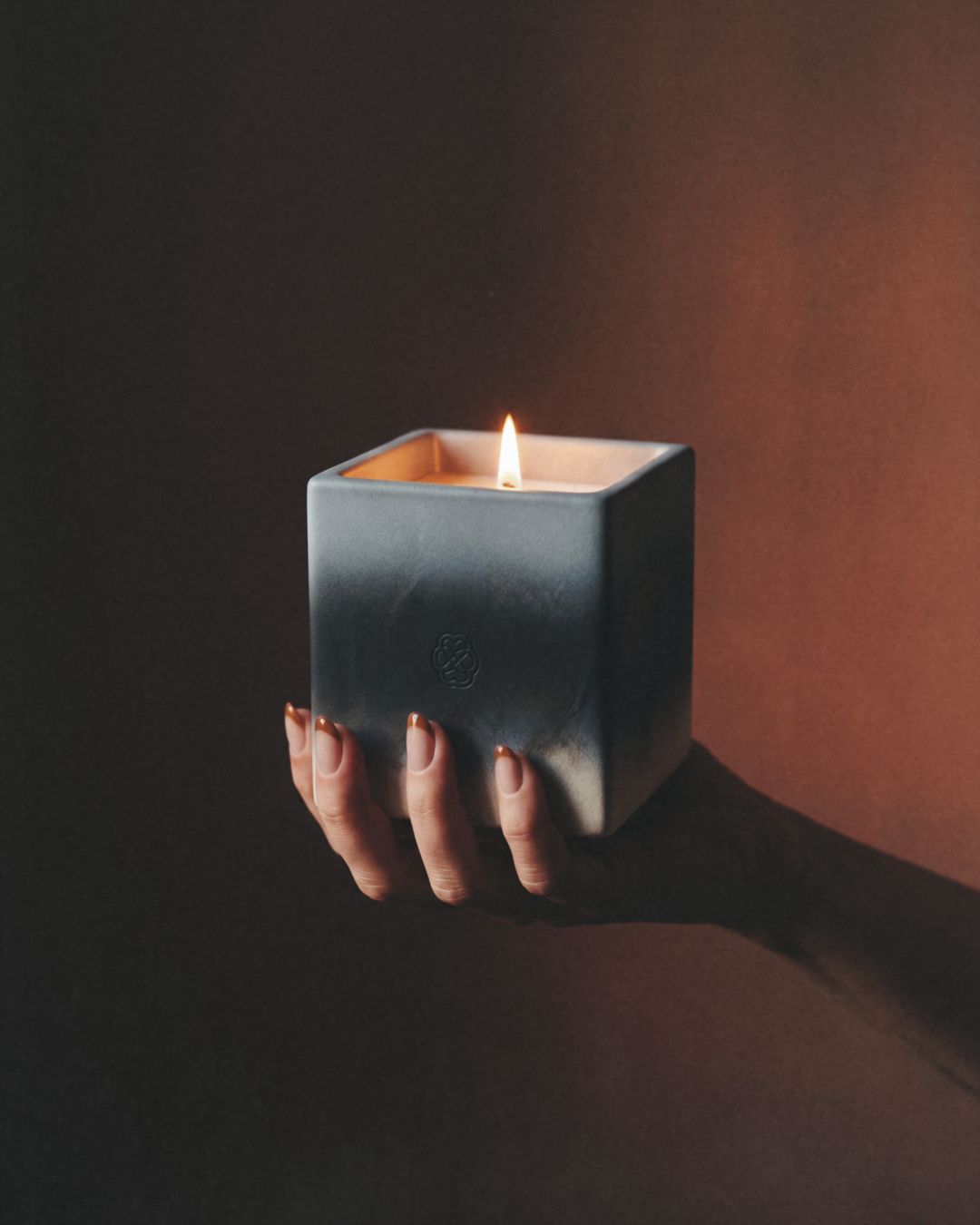Serein: mano sosteniendo una vela aromática encendida en un recipiente de cerámica